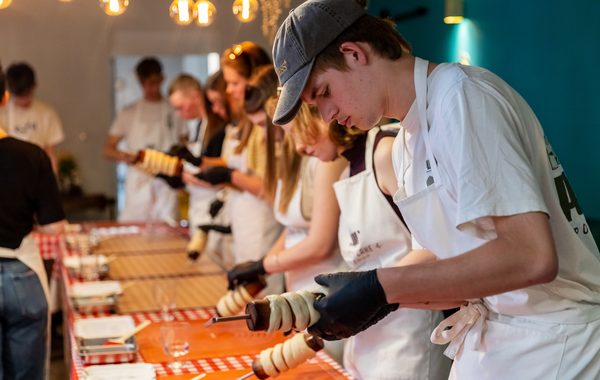 Guests rolling chimney cake dough onto wooden spits at the workshop