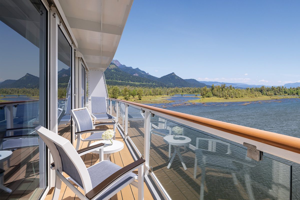 Lounge chairs on a private balcony aboard American Cruise Lines&rsquo; American Encore, overlooking the Columbia River and the mountains of the Columbia River Gorge
