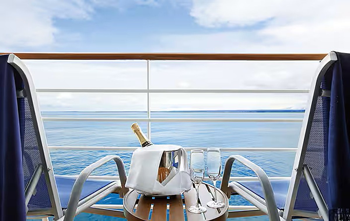 Two balcony chairs on an Oceania Cruises ship, with a bucket of champagne and two flutes on a small table overlooking the sea