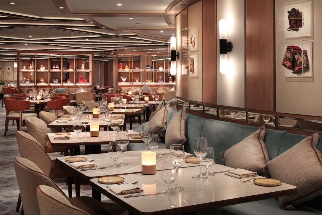 Elegant table settings, flickering candles and backlit display shelves inside the S.A.L.T. Kitchen restaurant aboard a Silversea ship
