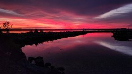 A crimson dusk sky reflects in still coastal water in Nova Scotia
