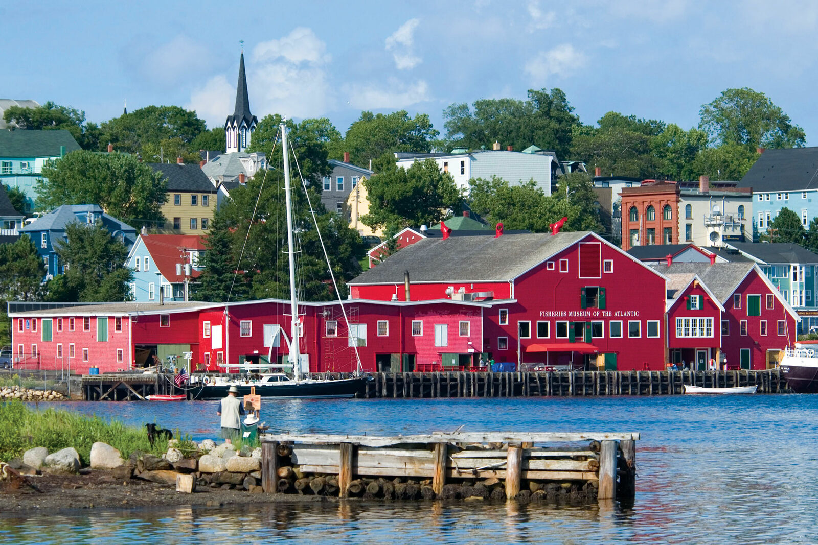 The bright red buildings of the Fisheries Museum of the Atlantic line Lunenburg's waterfront beneath the town's church spire
