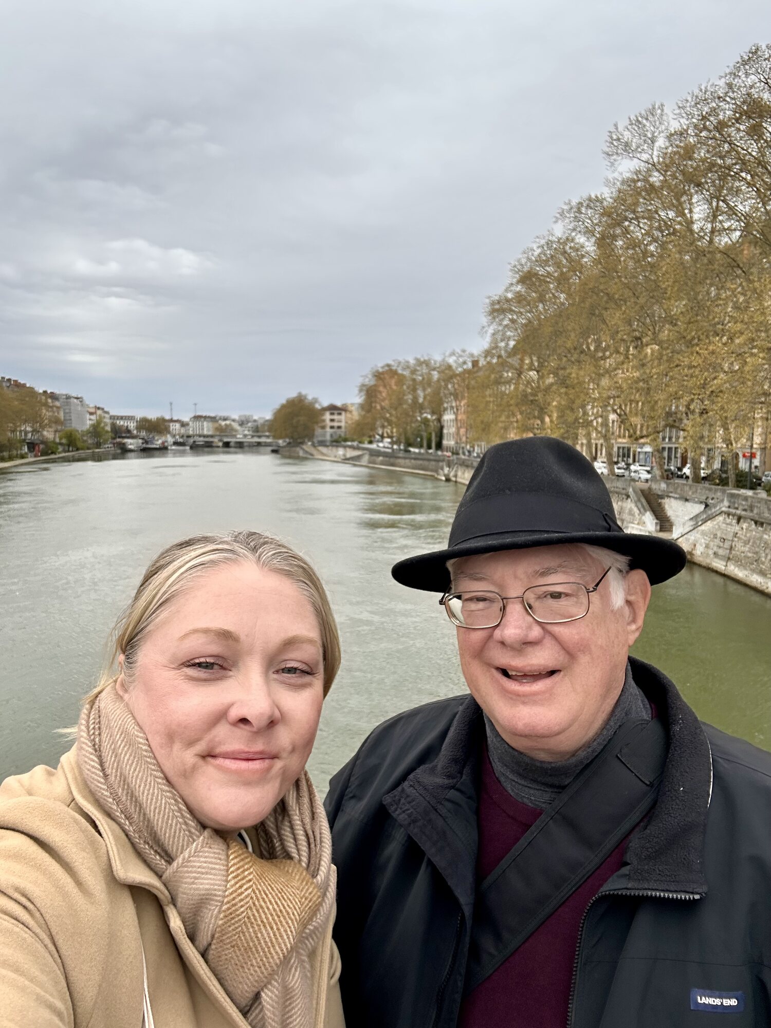 Sarah and Lewis take a selfie along a Lyon riverbank on an overcast day