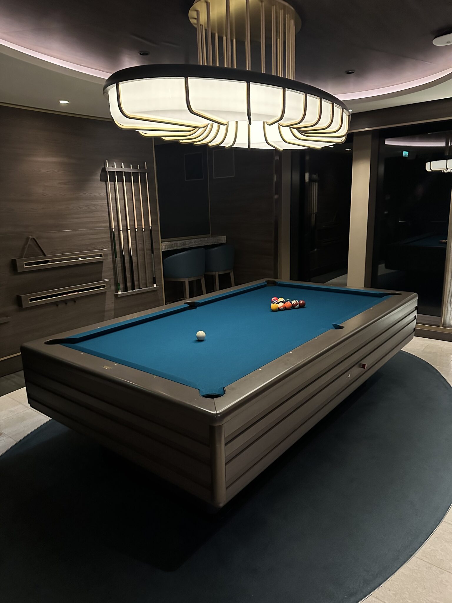 Designer billiards table under a dramatic art deco chandelier in the games lounge aboard Explora Journeys