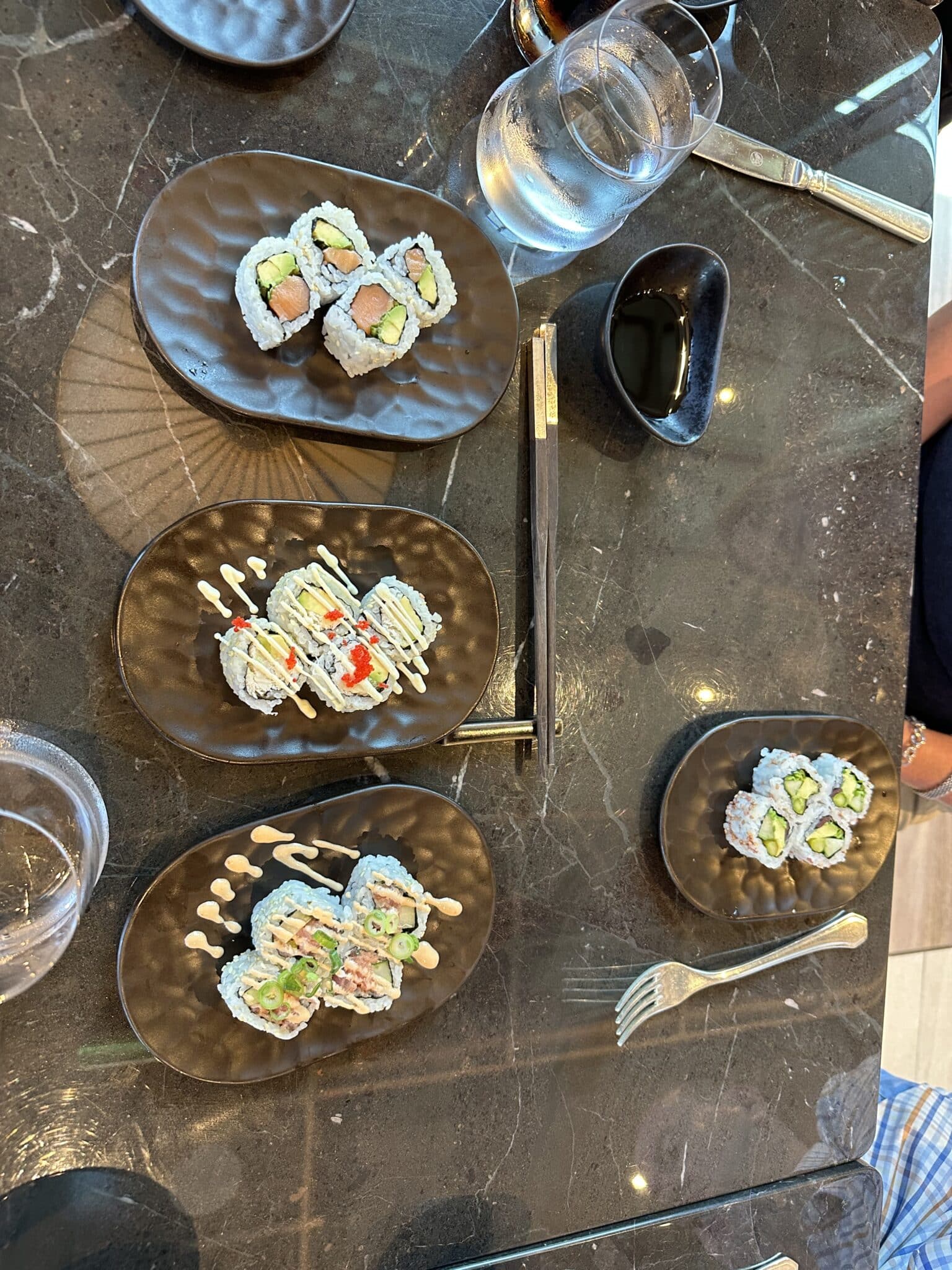 Assorted sushi rolls on dark ceramic plates at Sakura aboard Explora Journeys