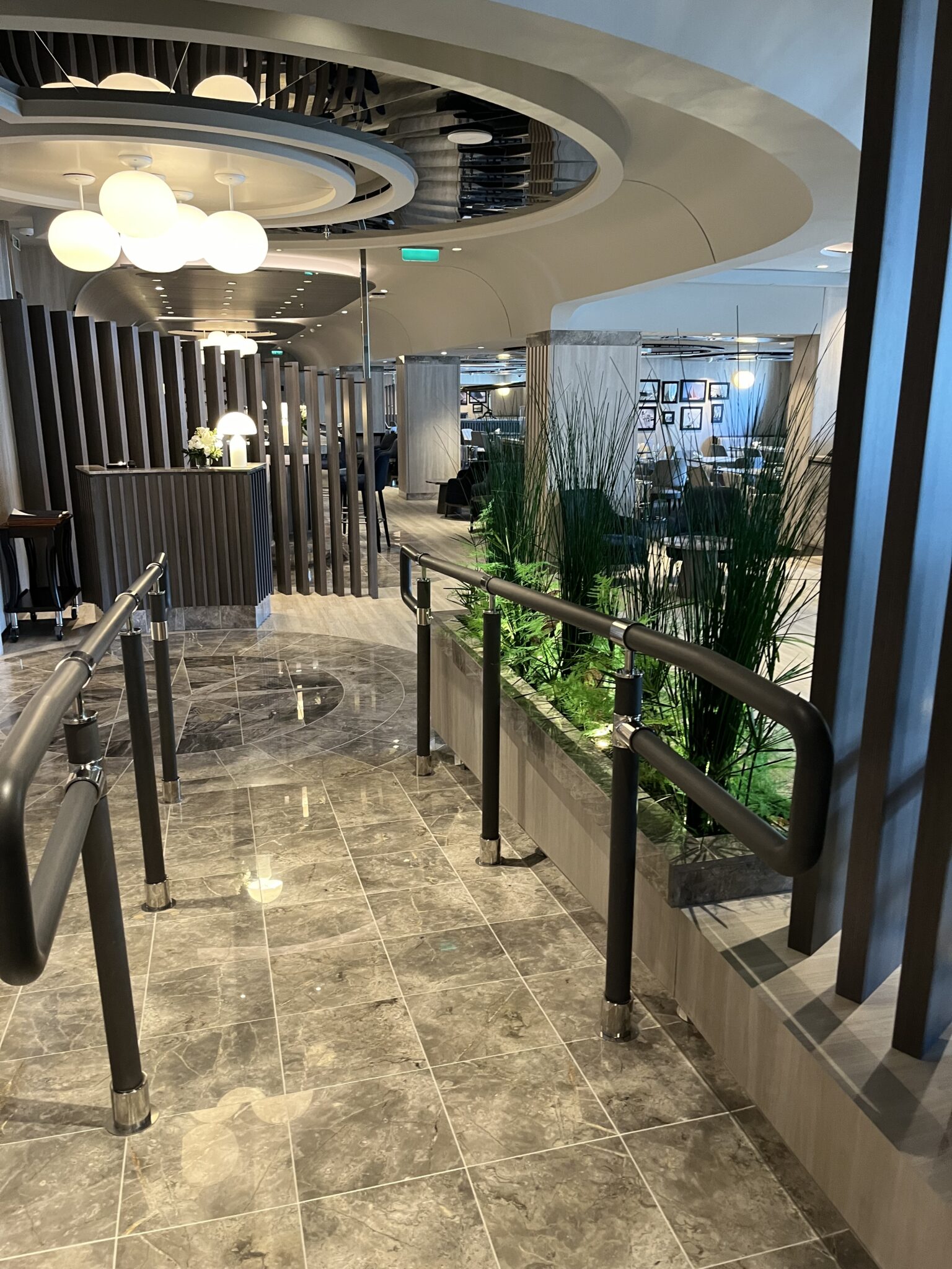 Spiraling multilevel restaurant interior with curved architecture and soft lighting aboard Explora Journeys